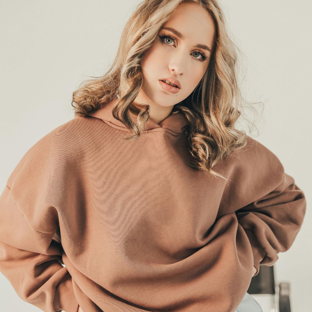Model wearing a tan fleece hoodie or sweatshirt.
