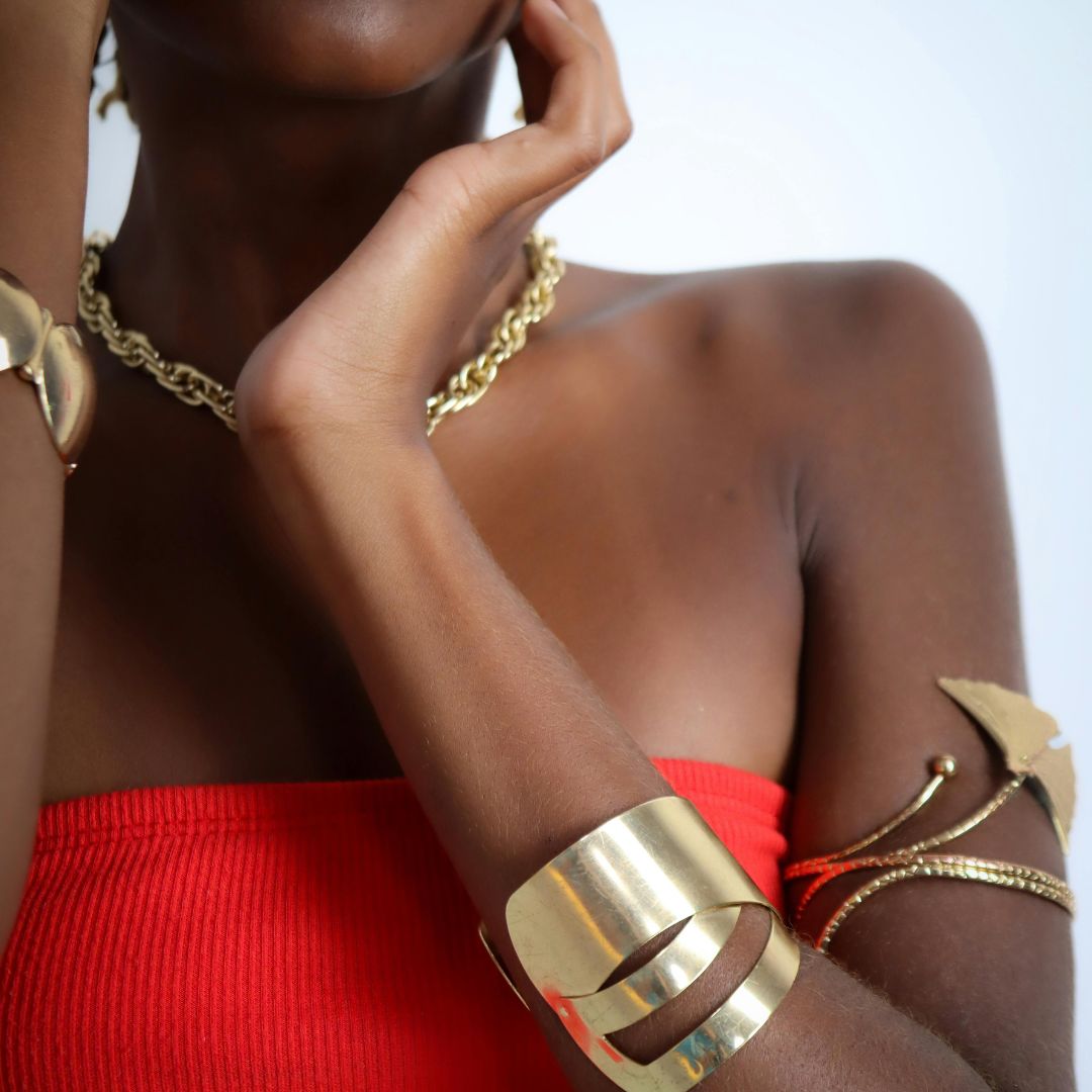 Model wearing stacked metallic bangles and jewelry.